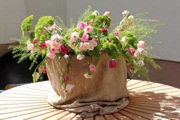 Obraz premium A bouquet of flowers in pots of burlap on a wooden stand on the street