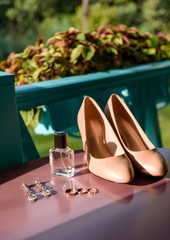 Wedding accessories, selective focus. Bridal shoes, earrings, perfume bottle, three wedding and engagement rings. Wedding details outdoors. Wedding morning concept, free space