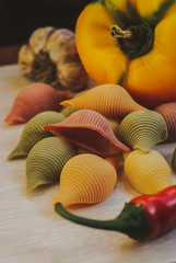 closeup of gluten free colorful conchiglioni pasta on wooden background.