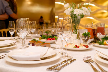 Sparkling glassware stands on round table prepared for wedding dinner in restaurant. Table setting, selective focus. Table served for wedding banquet