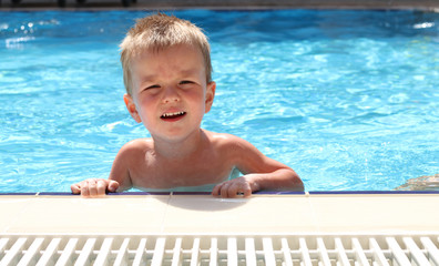 The blond boy learning to swim in the pool
