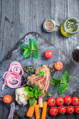Lamb shank dinner, with vegetables, parsley, mint jam and red wine on black rustic wooden table, top view, copy space