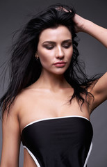 Fototapeta premium Portrait of a young brunette woman with long black streaming hair