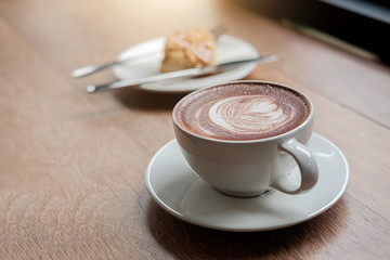 Cup of coffee on wooden table and bakery background in coffee shop