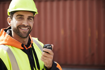 Smiling docker guy in hardhat with radio, portrait