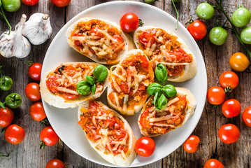 Traditional bruschetta with tomatoes and basil, spicy italian snack, overhead on plate for party and sharing with friends