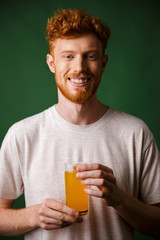 Portrait of handsome bearded man holding glass of orange juice