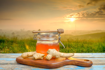 Alternative Medicine with garlic and  honey on wooden table. Beautiful sunrise as background.