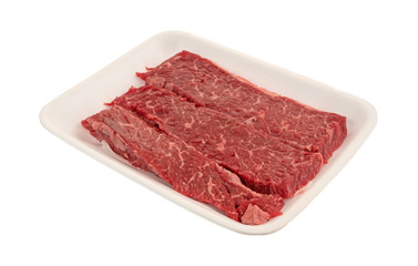 Raw beef loin sirloin grilling tips on a foam butcher tray isolated on a white background.
