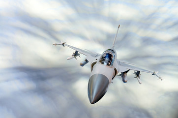 Military fighter aircraft at high speed, flying high in the sky.