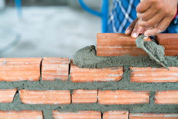 Construction worker build home by use cement mortar  to lay brick wall with a trowel follow vertical and horizontal guid line