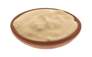 Side view of a small bowl filled with caramel yogurt isolated on a white background.