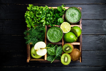 Green smoothie on dark wooden background. Healthy smoothie cocktail. Green vegetables and fruits. Healthy food and diet concept. Top view