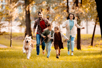 family running with dog in park - Powered by Adobe