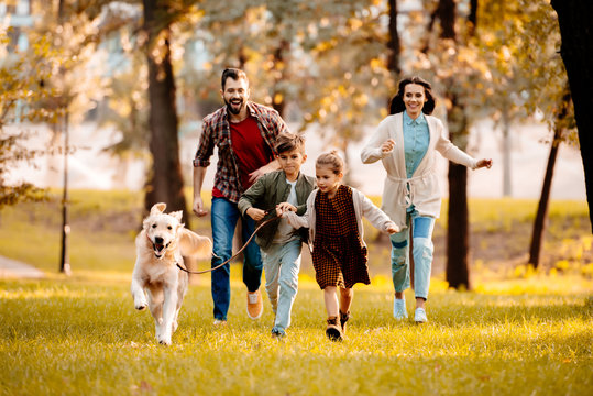 family running with dog in park