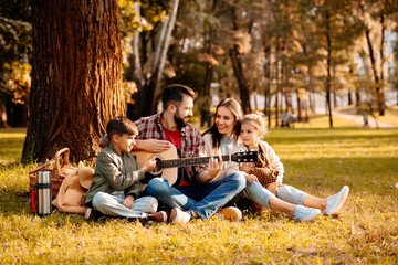 Family on picnic playing guitar