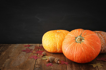 Pumpkins and autumn leaves on wooden background. thanksgiving and halloween concept