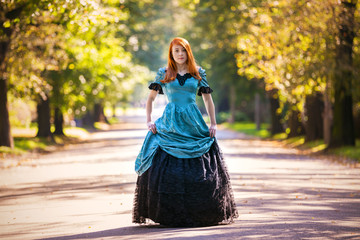 Red-haired woman in Victorian dress with autumn park