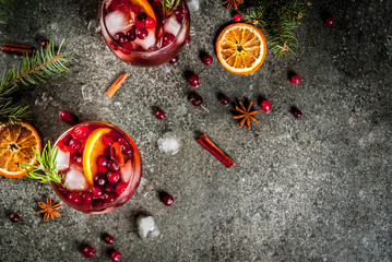 Christmas winter drinks. Cold cocktail with cranberries, orange, rosemary, with spices (cinnamon, anise) and ice, on a dark stone table, Copy space  TOP VIEW © ricka_kinamoto