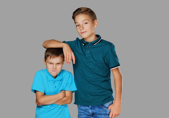 A boy put his arm on the head of an angry small boy.