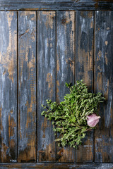 Bundle of fresh organic herbs oregano with garlic over old wooden plank background. Top view with copy space. Food background