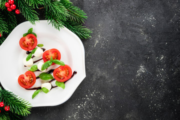 Caprese salad in the shape of christmas tree. Festive appetizer on dark table. Christmas table...