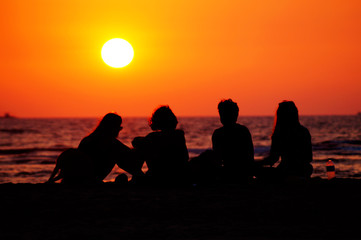 Group of friends on the beach. Happy moments of life. People silhouette on the sunset.
