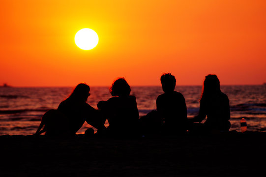 Group of friends on the beach. Happy moments of life. People silhouette on the sunset. - Powered by Adobe