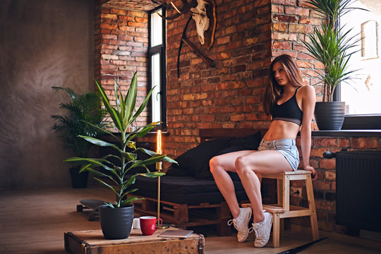 Attractive fitness female sits on a wooden sofa.