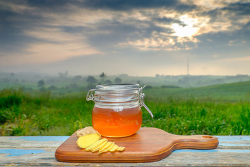 Alternative Medicine with garlic and  honey on wooden table. Beautiful sunrise as background.