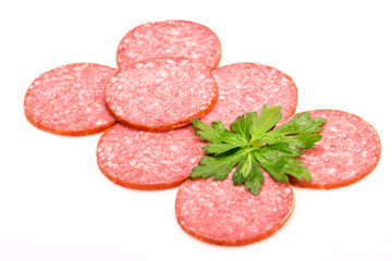 Smoked salami sausage. Sliced smoked sausage salami isolated on white background. Pieces of smoked sausage decorated with parsley leaves. Neatly sliced smoked sausage for advertising. Space for text.