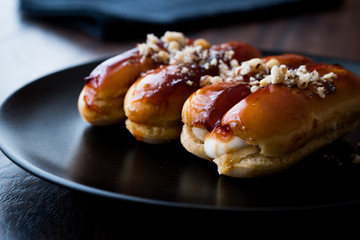 Caramel Eclairs with Hazelnut and cream in black plate.