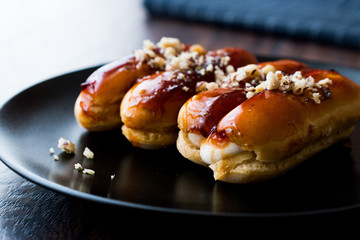 Caramel Eclairs with Hazelnut and cream in black plate.