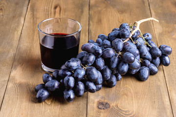 Black grapes and glass of wine on wooden background