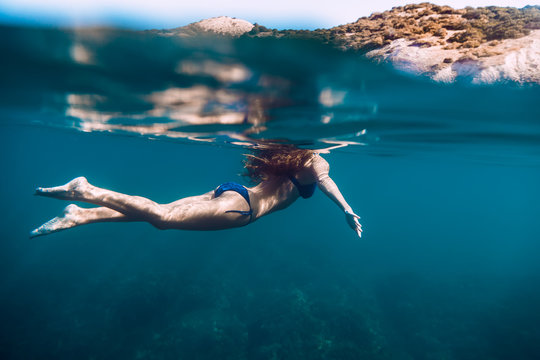Slim woman swimming in ocean, underwater photo