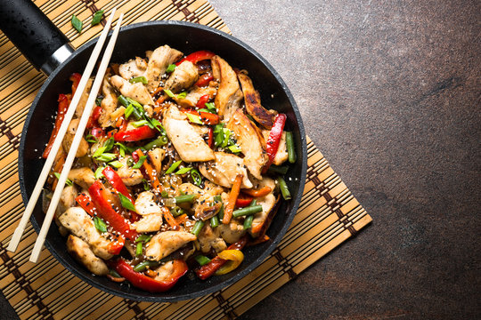 Chicken stir fry with vegetables at stone background. Top view copy space.