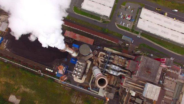 Camera flight over a modern combined heat and power plant. Fuming chimney with sulphur removal unit. Heavy industry from above. Power and fuel generation in European Union. 