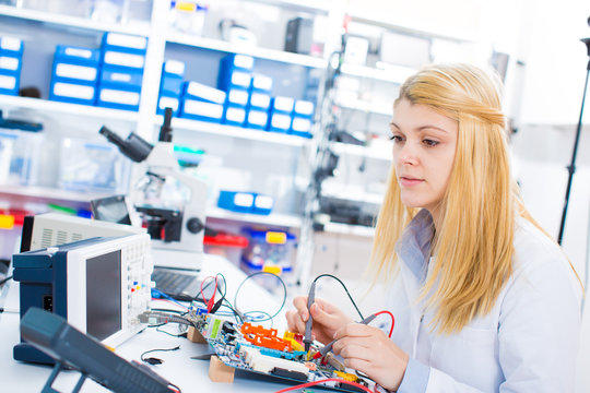 Female laboratory assistant Repairs PCB module for CNC robotics. Measurement of the parameters of the electronic system in the laboratory