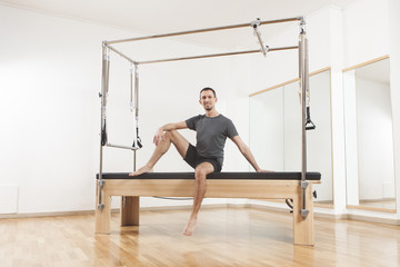 Pilates instructor performing exercise on cadillac equipment