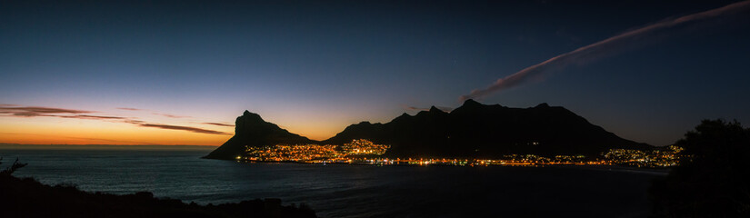 The sun sets behind Hout Bay, with the Sentinel Peak silhouetted against the golden light
