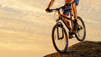 Naklejka na ściany i meble Cyclist Riding the Bike Down the Rock at Sunset. Extreme Sport and Enduro Biking Concept.