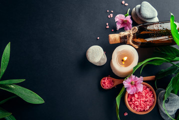 Spa essentials including candle, salt, stones, oil and green leaves