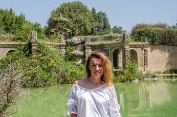 Young beautiful girl on the background of an antique fountain while walking in the park at Villa...
