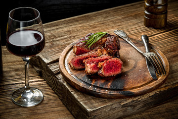 Grilled ribeye beef steak with red wine, herbs and spices on wooden table