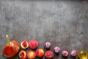 A glass of smoothies made of peach and plums on a wooden background