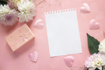 Blank notepad page with dahlias and gift box on a pink background. Copy space.