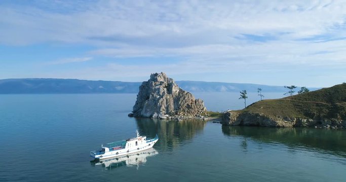 Tranquil Aerial View of the Baikal Bay Shamanka. White ship in calm bay at great lake. Olkhon Island, Baikal, Russia, Siberia. Drone footage.