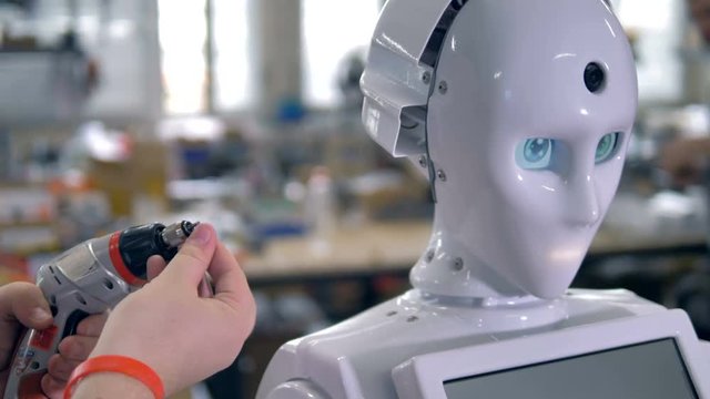 Engineer working on humanlike robots head in close-up view. 4K.