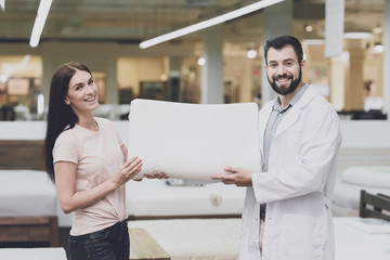 Orthopedic consultant helps a woman choose an orthopedic pillow. He shows her one of the pillow options
