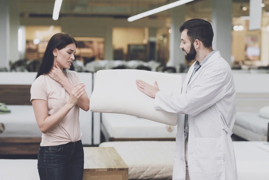 Orthopedic consultant helps a woman choose an orthopedic pillow. He shows her one of the pillow options